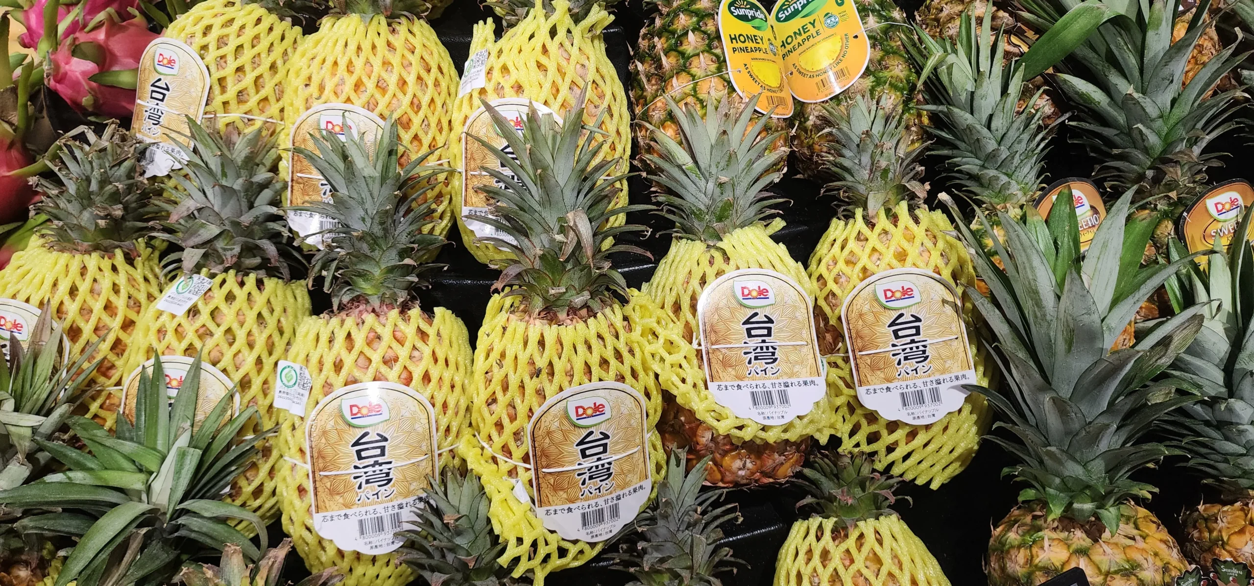 Fresh pineapples displayed in protective foam sleeves at a supermarket