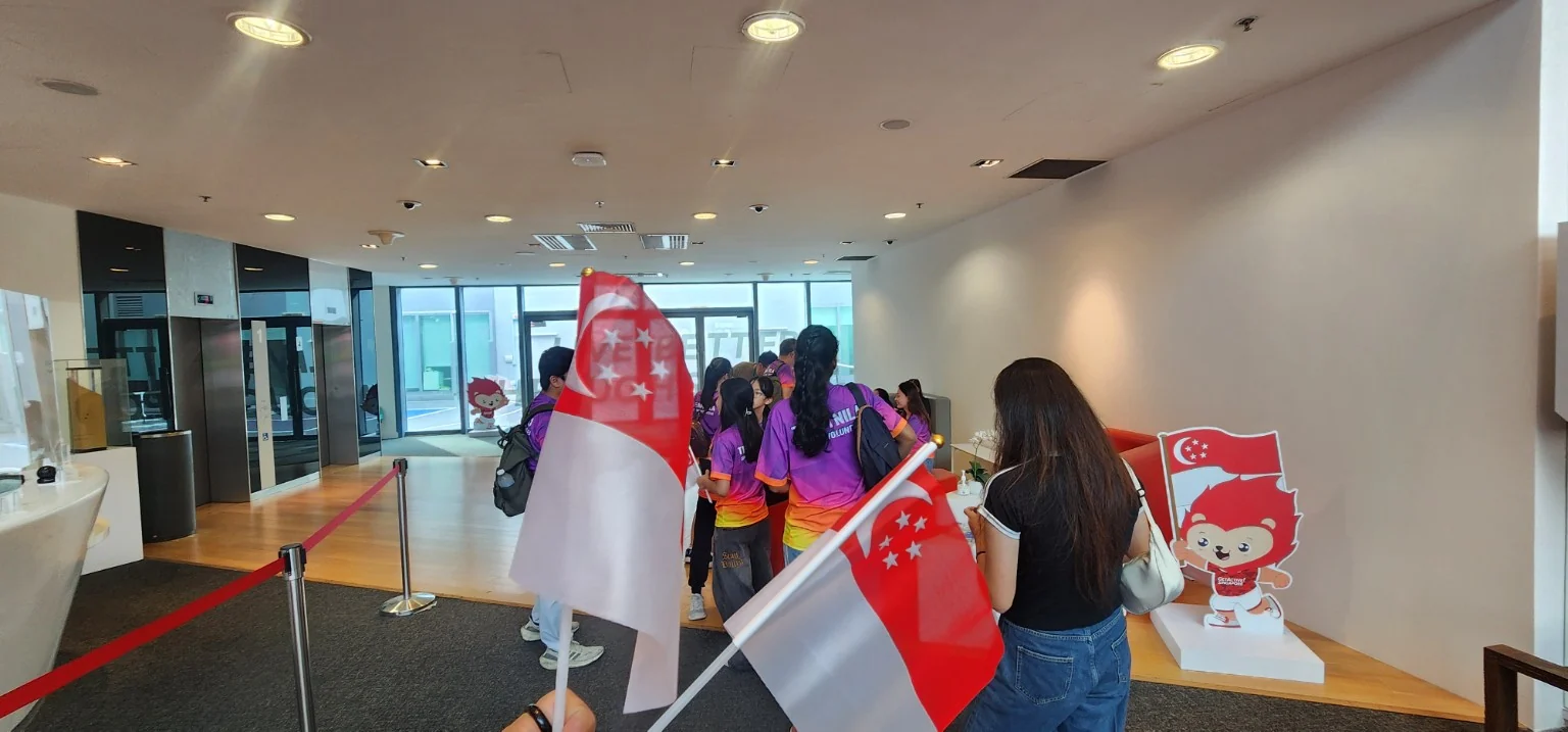 Team Nila volunteers with Singapore flags at the KFF Singapore Badminton Open 2026