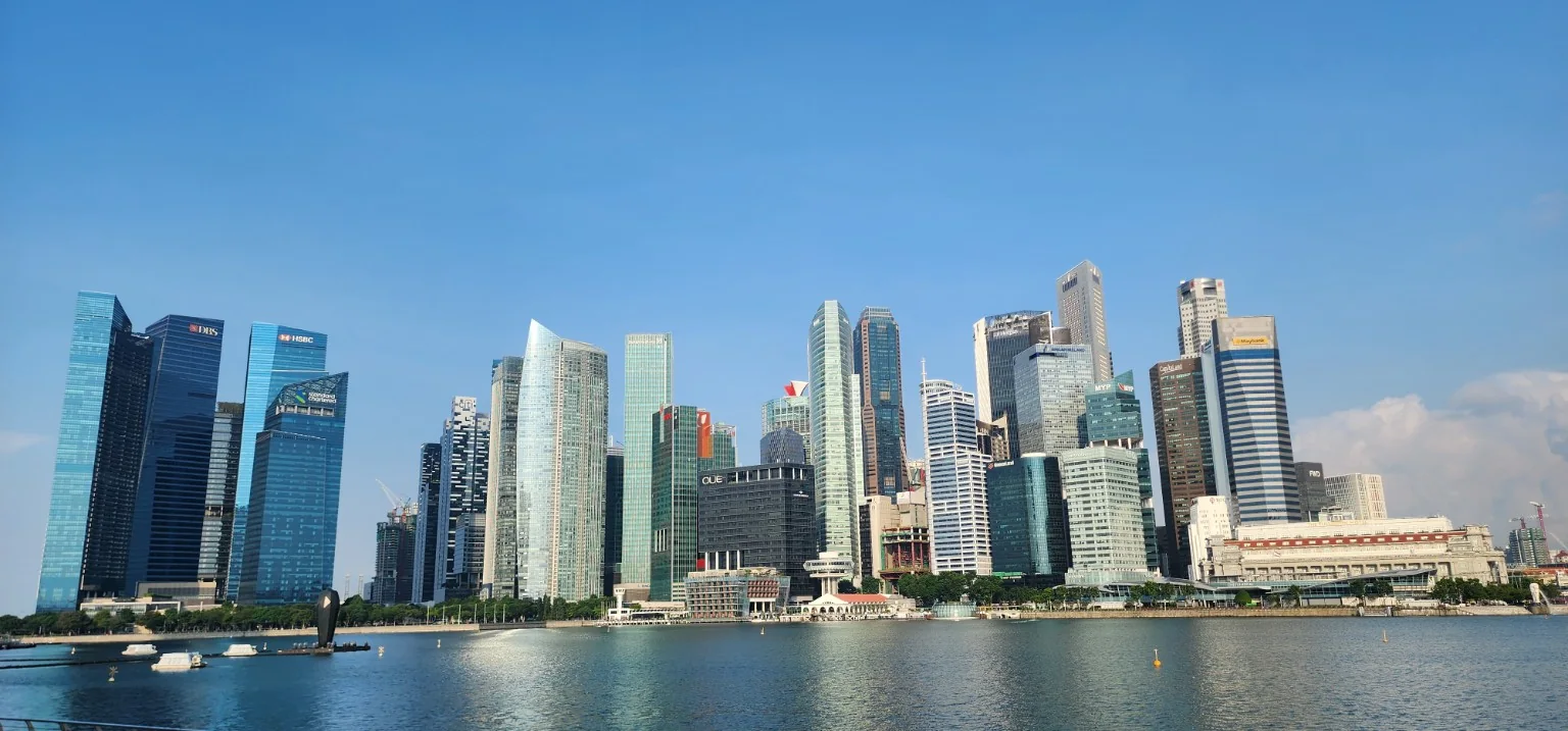 Singapore city skyline across Marina Bay under a clear blue sky