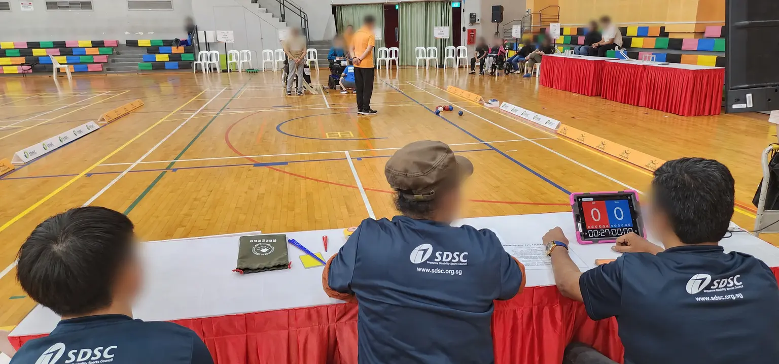 Boccia officials managing scoring and timing beside a competition court