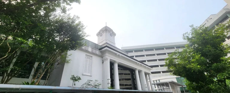 Bowyer Block clock tower at Singapore General Hospital, framed by trees.