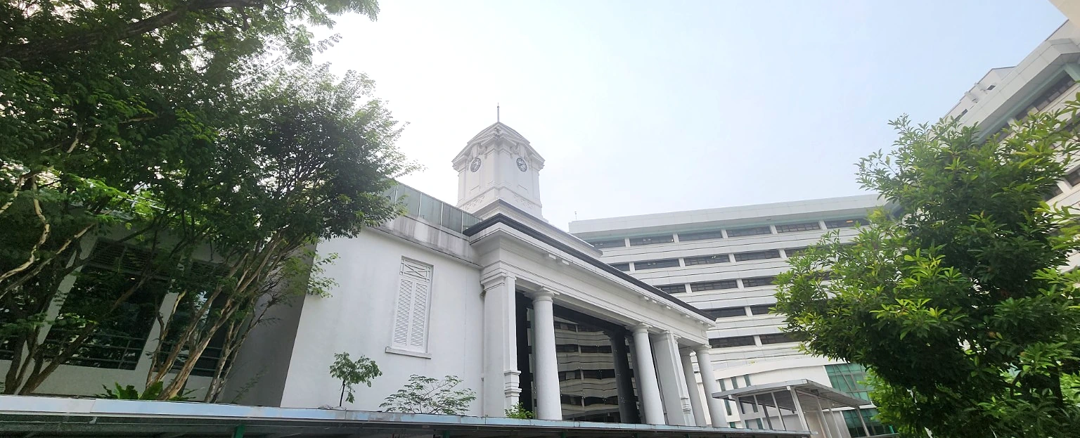 Bowyer Block clock tower at Singapore General Hospital, framed by trees.