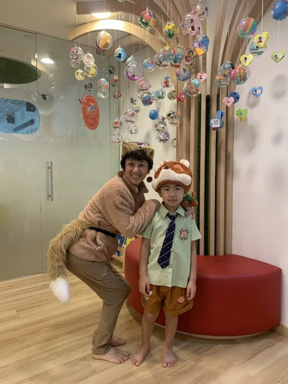 Ms Chris and a child wearing animal-themed costumes inside the preschool.