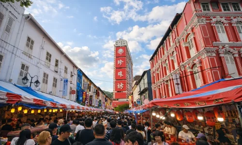 Chinatown street scene in Singapore with colourful shophouses, lanterns and a busy crowd.